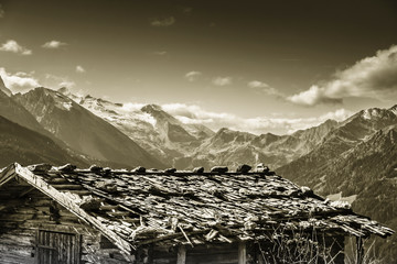 Blick über ein Schindeldach zu einem Gletscher im Zillertal in Sepia