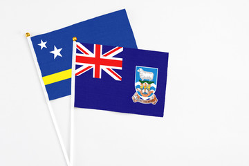 Fototapeta premium Falkland Islands and Curacao stick flags on white background. High quality fabric, miniature national flag. Peaceful global concept.White floor for copy space.