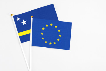 European Union and Curacao stick flags on white background. High quality fabric, miniature national flag. Peaceful global concept.White floor for copy space.