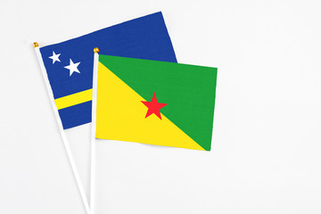 French Guiana and Curacao stick flags on white background. High quality fabric, miniature national flag. Peaceful global concept.White floor for copy space.