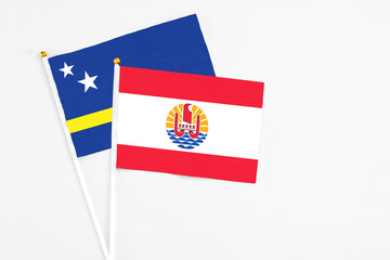 French Polynesia and Curacao stick flags on white background. High quality fabric, miniature national flag. Peaceful global concept.White floor for copy space.