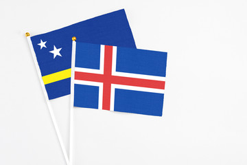 Obraz premium Iceland and Curacao stick flags on white background. High quality fabric, miniature national flag. Peaceful global concept.White floor for copy space.