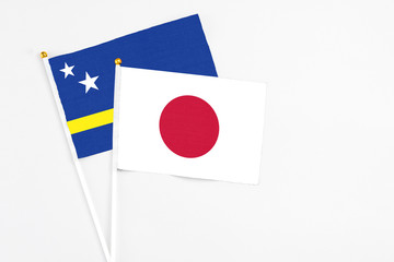 Japan and Curacao stick flags on white background. High quality fabric, miniature national flag. Peaceful global concept.White floor for copy space.