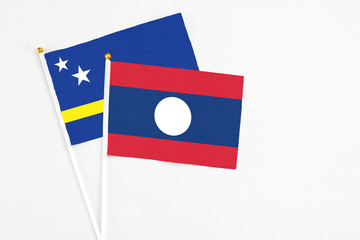 Laos and Curacao stick flags on white background. High quality fabric, miniature national flag. Peaceful global concept.White floor for copy space.