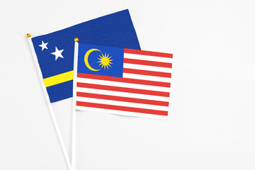 Malaysia and Curacao stick flags on white background. High quality fabric, miniature national flag. Peaceful global concept.White floor for copy space.