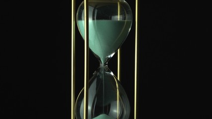 Hourglass clock time concept. Old vintage gold metal frame green sand clock countdown on dark...