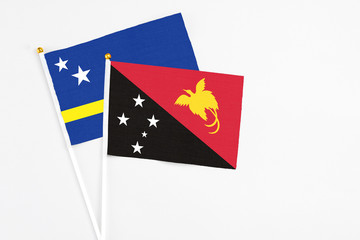 Papua New Guinea and Curacao stick flags on white background. High quality fabric, miniature national flag. Peaceful global concept.White floor for copy space.
