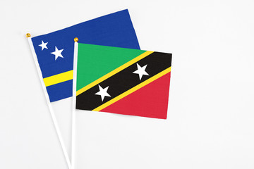 Saint Kitts And Nevis and Curacao stick flags on white background. High quality fabric, miniature national flag. Peaceful global concept.White floor for copy space.