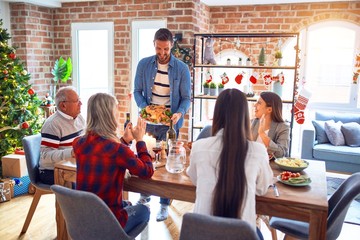 Beautiful family meeting smiling happy and confident. Person standing holding roasted turkey celebrating Christmas at home