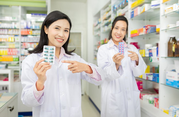 two asian pharmacist standing in drugstore, they feeling happy and smile, teamwork and professional...