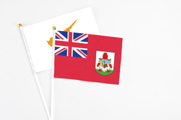 Fototapeta premium Bermuda and Cyprus stick flags on white background. High quality fabric, miniature national flag. Peaceful global concept.White floor for copy space.