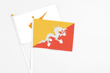 Bhutan and Cyprus stick flags on white background. High quality fabric, miniature national flag. Peaceful global concept.White floor for copy space.
