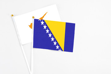 Bosnia Herzegovina and Cyprus stick flags on white background. High quality fabric, miniature national flag. Peaceful global concept.White floor for copy space.