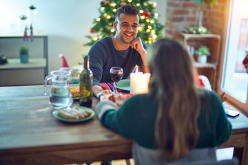 Young beautiful couple smiling happy and confident. Eating food celebrating christmas at home