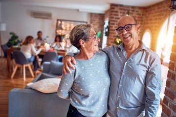 Family and friends dining at home celebrating christmas eve with traditional food and decoration, romantic senior couple hugging in love