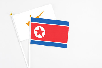 North Korea and Cyprus stick flags on white background. High quality fabric, miniature national flag. Peaceful global concept.White floor for copy space.