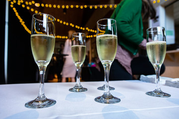 Selective focus of crystal glasses of alcoholic beverages standing on a buffet table with people standing in the background