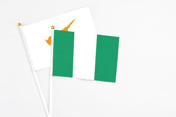 Nigeria and Cyprus stick flags on white background. High quality fabric, miniature national flag. Peaceful global concept.White floor for copy space.
