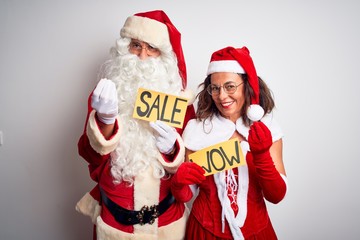 Couple wearing Santa costume holding wow and sale banner over isolated white background doing money gesture with hands, asking for salary payment, millionaire business