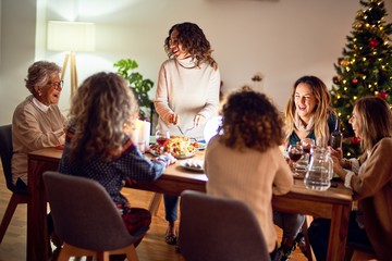 Beautiful group of women smiling happy and confident. Carving roasted turkey celebrating christmas at home