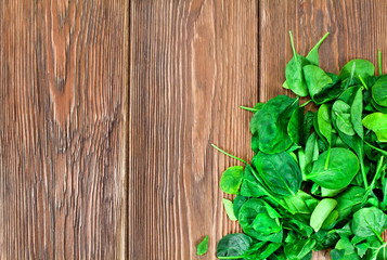 Leaves of spinach on wooden background. Top view. Copy space.