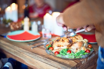 Beautiful family smiling happy and confident. One of them curving roasted turkey celebrating thanksgiving day at home