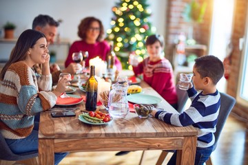 Beautiful family smiling happy and confident. Toddler standing holding cup of water speaking speech celebrating christmas at home