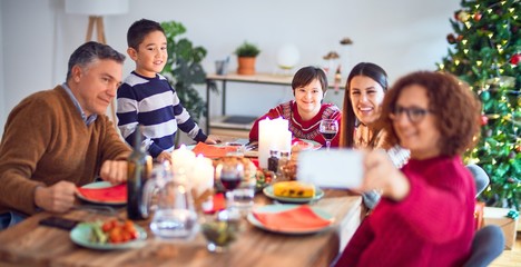 Beautiful family smiling happy and confident. Eating roasted turkey make selfie by smartphone celebrating christmas at home