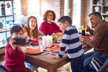 Beautiful family smiling happy and confident. Eating roasted turkey make selfie by smartphone celebrating christmas at home