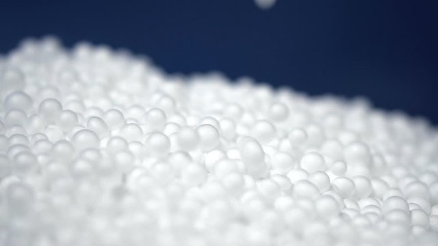 White round polystyrene packaging material drop from injection machine in slow motion, modern foam bead ball decoration cause global warming from chemical waste