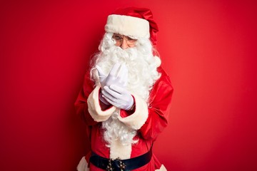 Middle age handsome man wearing Santa costume standing over isolated red background Suffering pain on hands and fingers, arthritis inflammation