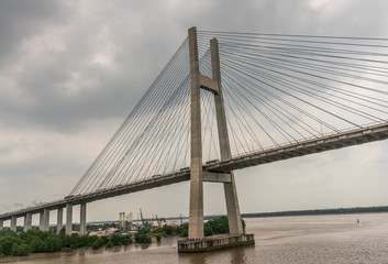 Ho Chi Minh City, Vietnam - March 12, 2019: Long Tau and song Sai Gon rivers meeting point. Landscape with  H-shaped pylon of Phu My suspension bridge in center under gray cloudscape. Brown water.