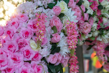 Many artificial bouquets of pink flowers with bokeh lighting.