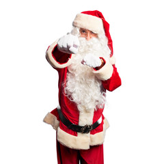 Middle age handsome man wearing Santa Claus costume and beard standing Punching fist to fight, aggressive and angry attack, threat and violence