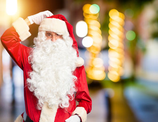 Middle age handsome man wearing Santa Claus costume and beard standing confuse and wondering about...
