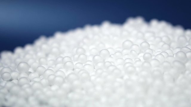 White round polystyrene packaging material drop from injection machine in slow motion, modern foam bead ball decoration cause global warming from chemical waste