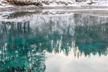 Beautiful reflection in the water on a blue ice-free lake in Altai. The beauty of winter in the Altai. Russia, Altai Region, Siberia.