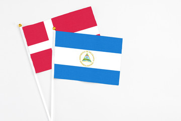 Nicaragua and Denmark stick flags on white background. High quality fabric, miniature national flag. Peaceful global concept.White floor for copy space.