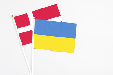 Ukraine and Denmark stick flags on white background. High quality fabric, miniature national flag. Peaceful global concept.White floor for copy space.