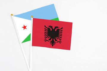 Albania and Djibouti stick flags on white background. High quality fabric, miniature national flag. Peaceful global concept.White floor for copy space.