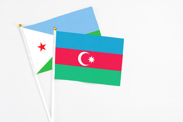 Azerbaijan and Djibouti stick flags on white background. High quality fabric, miniature national flag. Peaceful global concept.White floor for copy space.