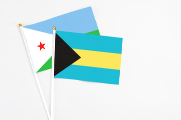 Bahamas and Djibouti stick flags on white background. High quality fabric, miniature national flag. Peaceful global concept.White floor for copy space.