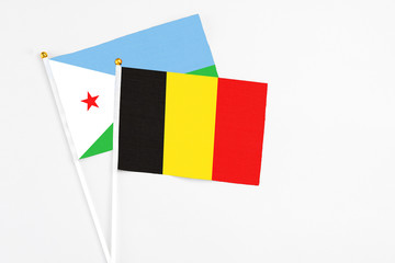 Belgium and Djibouti stick flags on white background. High quality fabric, miniature national flag. Peaceful global concept.White floor for copy space.