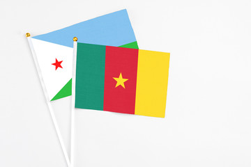Cameroon and Djibouti stick flags on white background. High quality fabric, miniature national flag. Peaceful global concept.White floor for copy space.