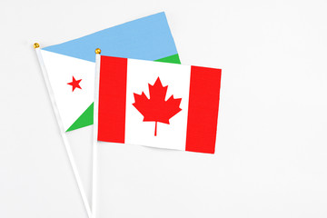 Canada and Djibouti stick flags on white background. High quality fabric, miniature national flag. Peaceful global concept.White floor for copy space.