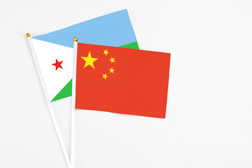 China and Djibouti stick flags on white background. High quality fabric, miniature national flag. Peaceful global concept.White floor for copy space.