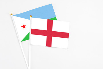 England and Djibouti stick flags on white background. High quality fabric, miniature national flag. Peaceful global concept.White floor for copy space.