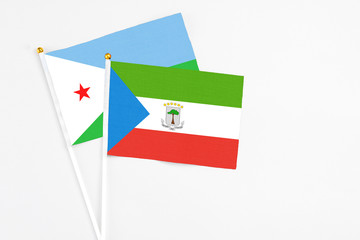 Equatorial Guinea and Djibouti stick flags on white background. High quality fabric, miniature national flag. Peaceful global concept.White floor for copy space.