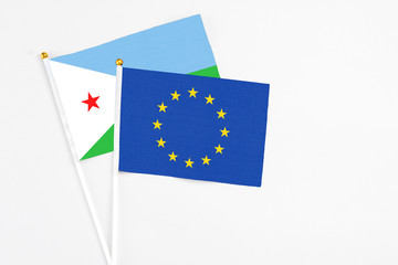European Union and Djibouti stick flags on white background. High quality fabric, miniature national flag. Peaceful global concept.White floor for copy space.