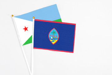 Guam and Djibouti stick flags on white background. High quality fabric, miniature national flag. Peaceful global concept.White floor for copy space.